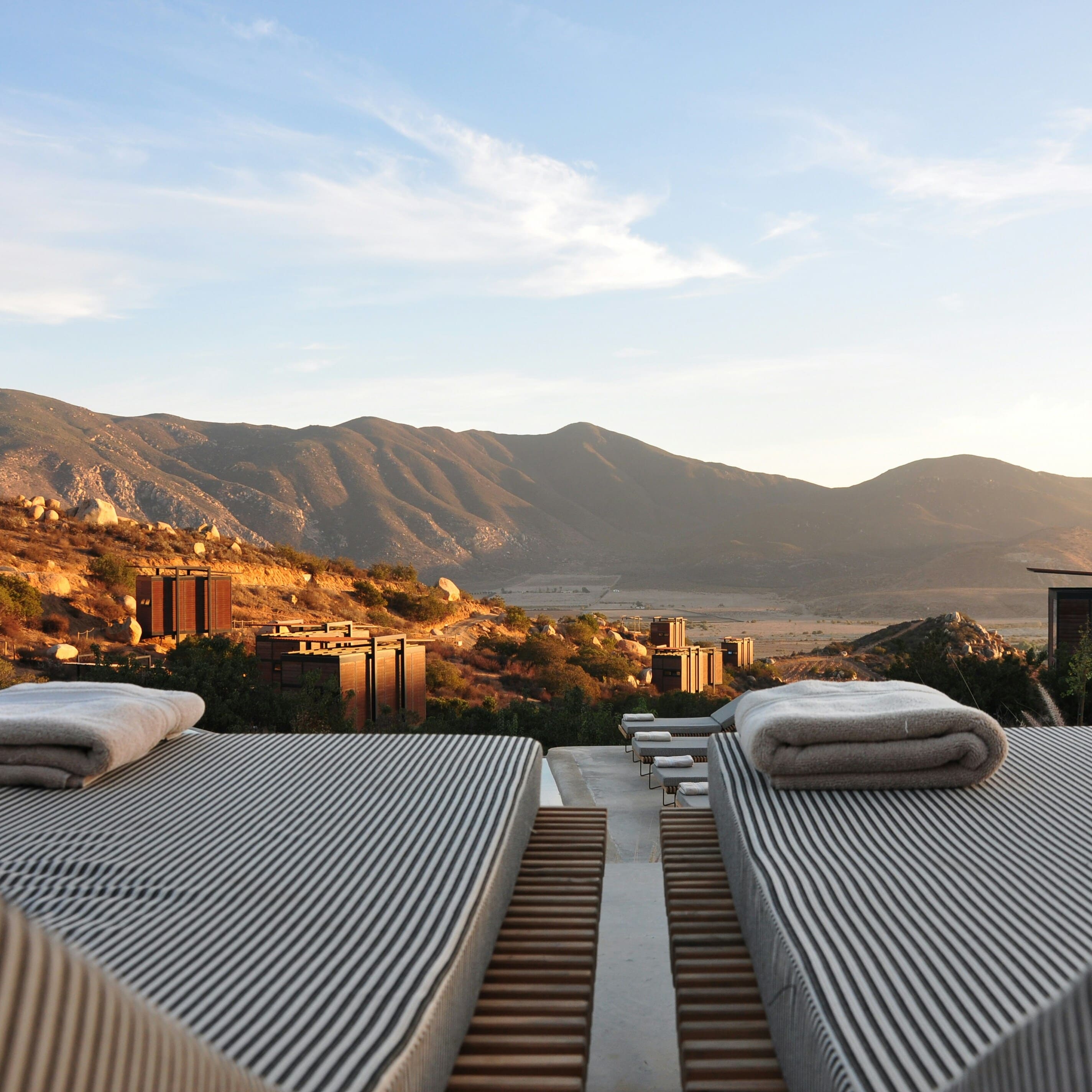 An image of two chairs overlooking a vast mountain range while the sun is setting