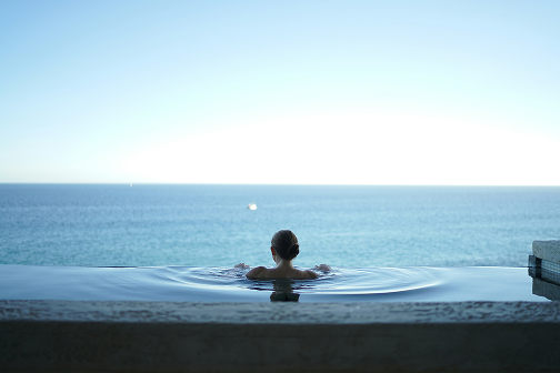 Person in a pool looking over the ocean