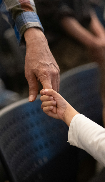 A small hand holding the finger of an older hand